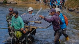 PLN Bersama Warga Bawa Panel Surya Menyebrang Sungai